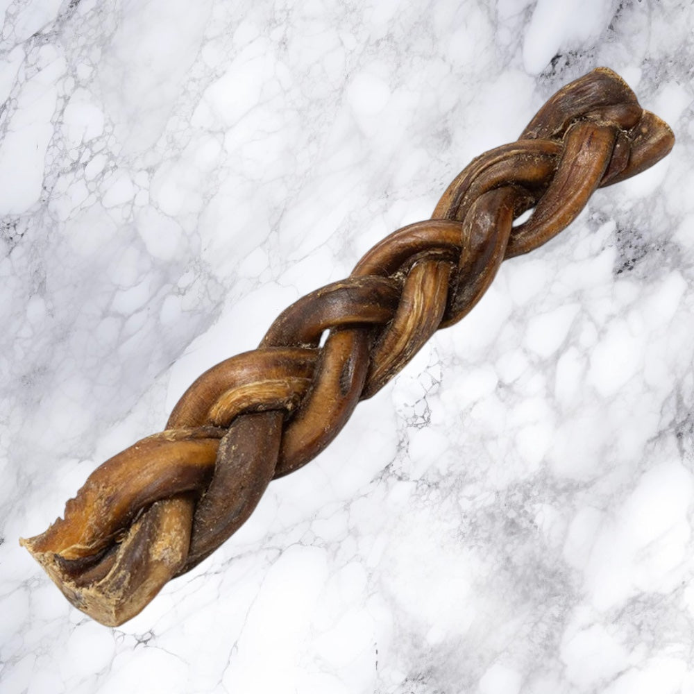 A Hilltop Pet Food Braided Pizzle Bully Stick dog chew rests on a white marble surface.