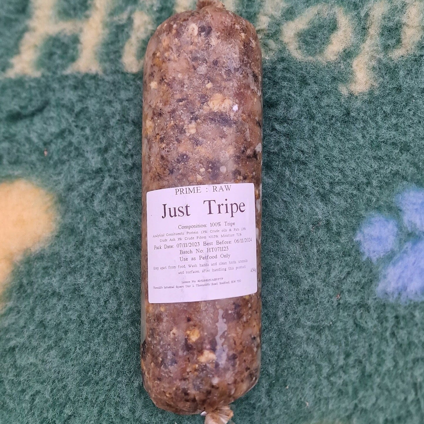 A roll of Hilltop Pet Food Prime:Raw - Just Tripe for working dogs rests on a green surface, label and instructions visible.
