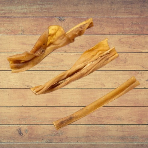 Three pieces of dried Goat Skin dog treats on a wooden surface