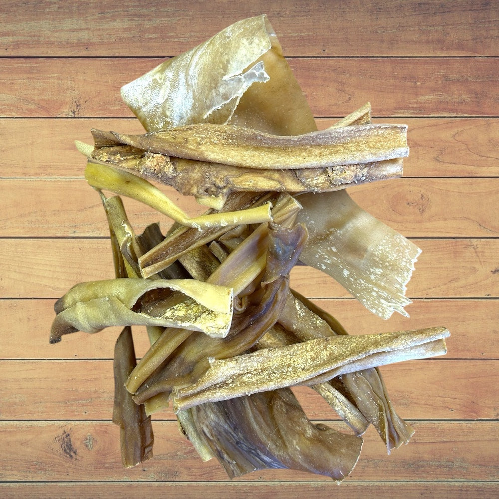 Stack of Dried Goat Skin dog treats on a wooden surface