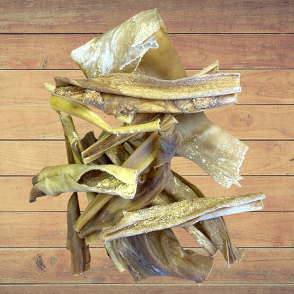 Stack of Dried Goat Skin dog treats on a wooden surface