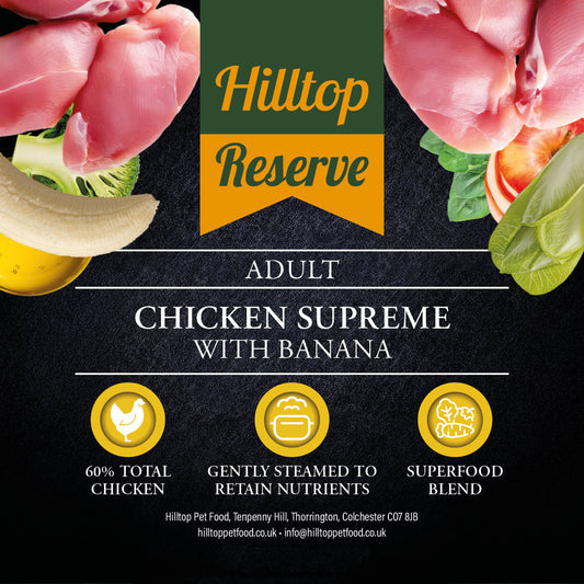 Promotional graphic for Hilltop Reserve Adult Chicken Supreme with Banana, featuring raw chicken pieces, banana, broccoli, and vegetables around a central green and orange logo banner on a dark textured background with product details and three benefit icons.