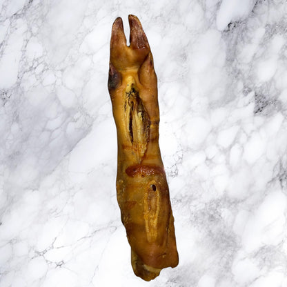A Hilltop Pet Food Large Pig Trotter - Dried dog chew on a white marble surface.