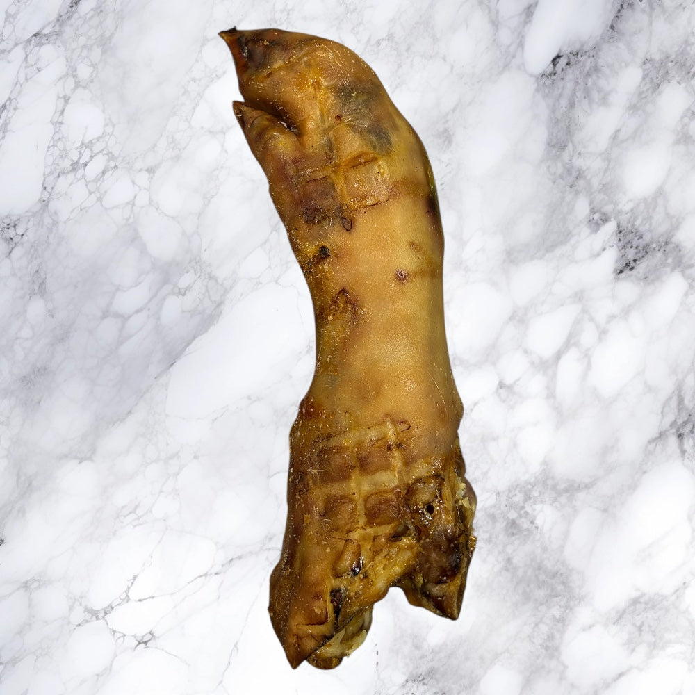 A Hilltop Pet Food Large Pig Trotter—dried and natural—rests on a white marble surface.
