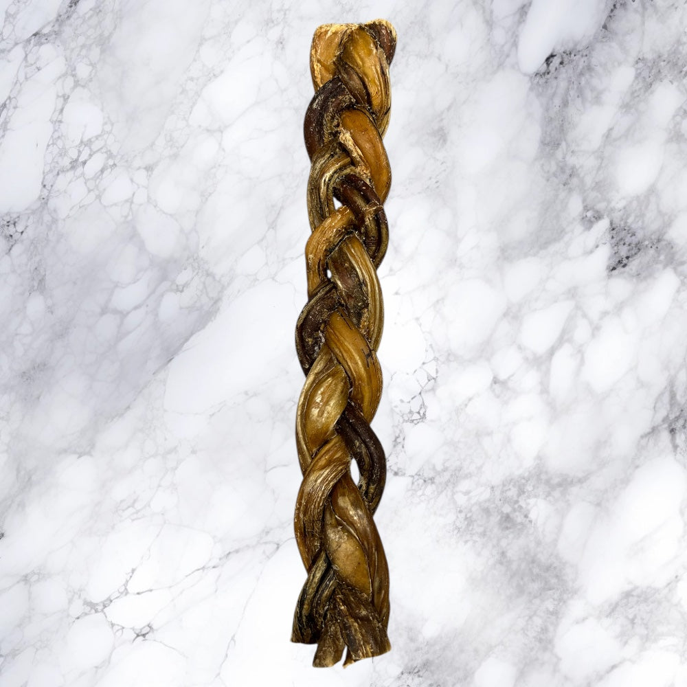 A long, braided loaf of bread on white marble, resembling Hilltop Pet Food’s Braided Pizzle Bully Stick dog treat.