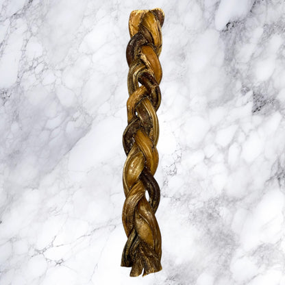 A long, braided loaf of bread on white marble, resembling Hilltop Pet Food’s Braided Pizzle Bully Stick dog treat.