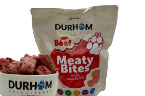 A 1kg bag of Hilltop Pet Food Durham Meaty Bites Beef with Veg & Supplements sits beside a bowl of dog food.