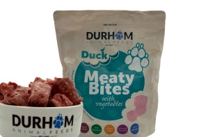 A 1kg bag of Hilltop Pet Food Durham Meaty Bites Duck with Veg & Supplements sits beside a bowl of treats.