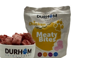 A 1kg bag of Hilltop Pet Food Durham Meaty Bites Chicken, pickup-only, behind a bowl of raw chicken pieces.