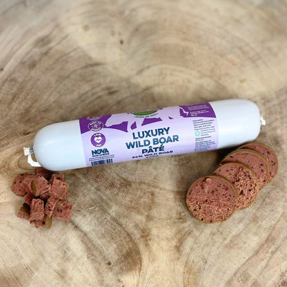 A tube of Hilltop Pet Foods Paddock Farm Luxury Pâté, Wild Boar flavor, beside sliced portions on wood.