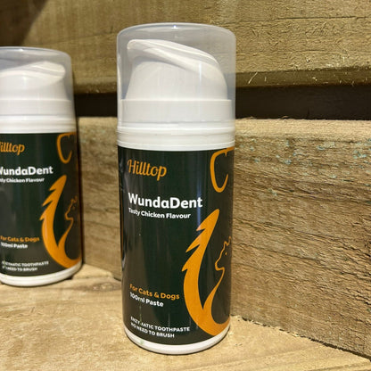 A tube of Hilltop Pet Food WundaDent No-brush Enzymatic Toothpaste for Dogs and Cats on a wooden surface.
