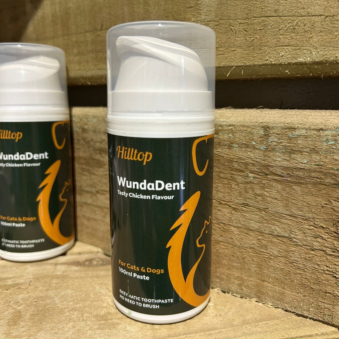 A tube of Hilltop Pet Food WundaDent No-brush Enzymatic Toothpaste for Dogs and Cats on a wooden surface.