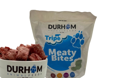 A bag of Hilltop Pet Food Durham Meaty Bites Tripe (1kg) with product badges and a bowl of red, chunky treats in front.