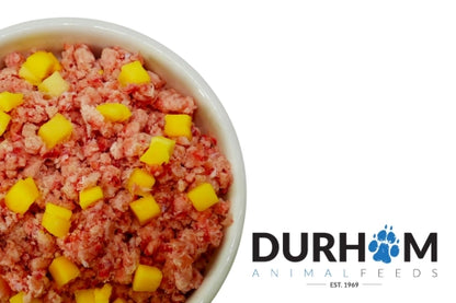 Dog food with yellow chunks in a bowl, branded with Durham Animal Feeds.