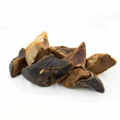 Several cracked brown and black Cow Hoof pieces by Hilltop Pet Food on white, resembling natural badges in texture.