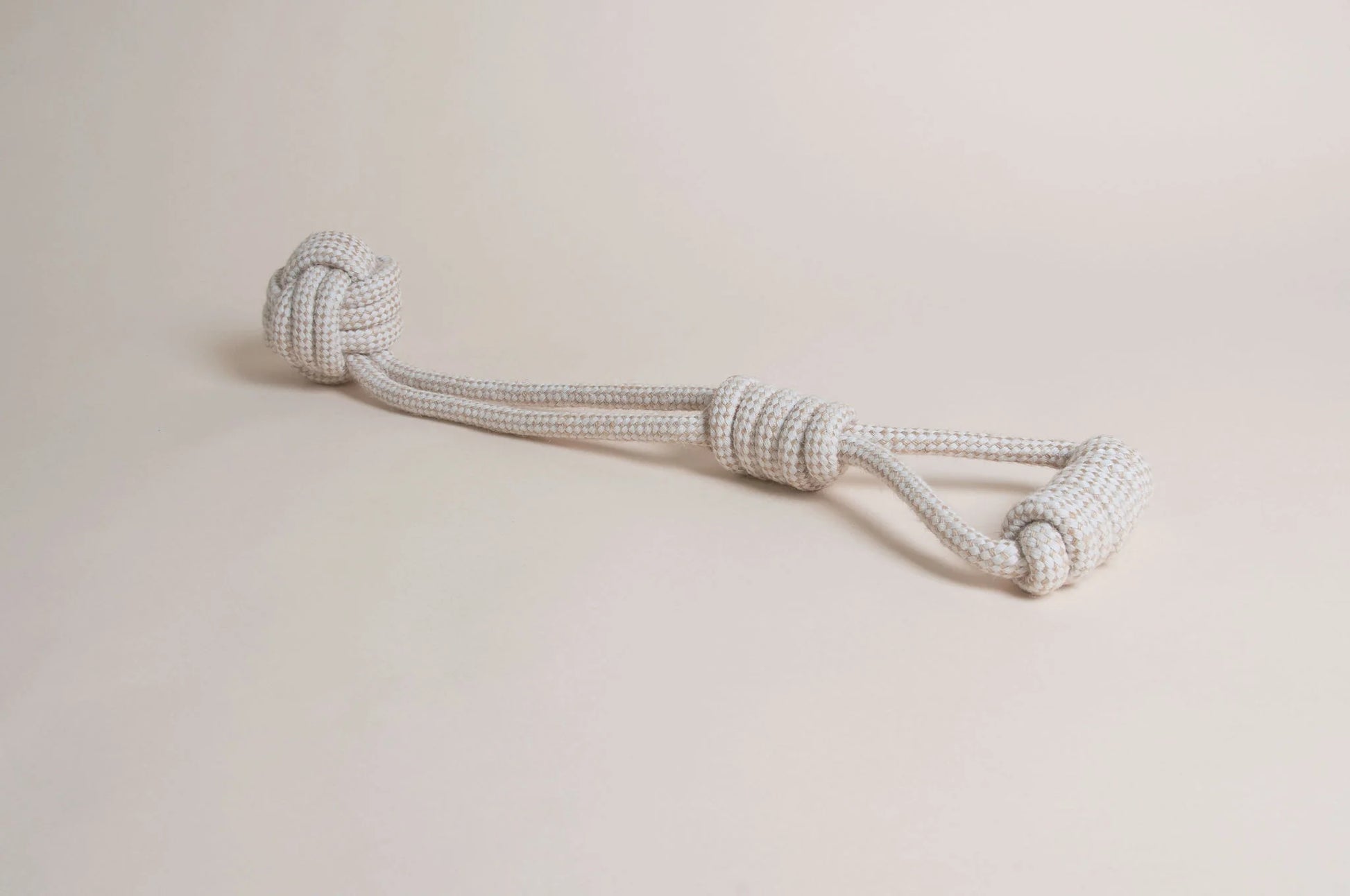 The Hilltop Pet Food Natural Rope Toy - Swingball Tug, white and gray with large end knots, sits on a light surface.