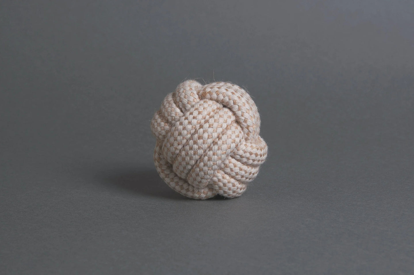 The Hilltop Pet Food Natural Rope Toy - Classic Rope Ball sits on a plain gray surface and background.