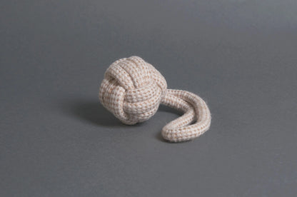 The Hilltop Pet Food Natural Rope Toy - Slingshot Ball is tied in a monkey’s fist knot with a loose end on gray.