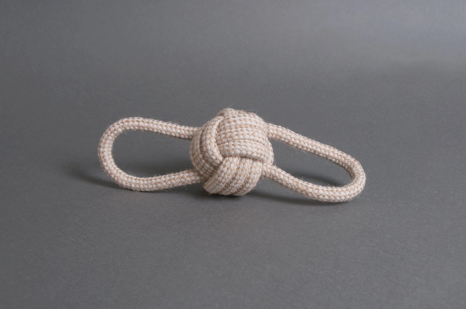 Hilltop Pet Foods Natural Rope Toy - Bow Tie Ball in white, featuring two loops, on a plain gray surface.