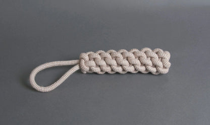 The Hilltop Pet Food Natural Rope Toy - Thug Tug is a beige loop-handle keychain inspired by organic dog toys.