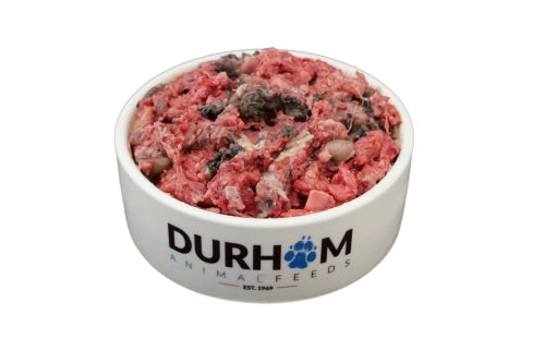 A white bowl labeled Durham Animal Feeds filled with Hilltop Pet Food Game & Tripe Complete Mince 454g, on white.